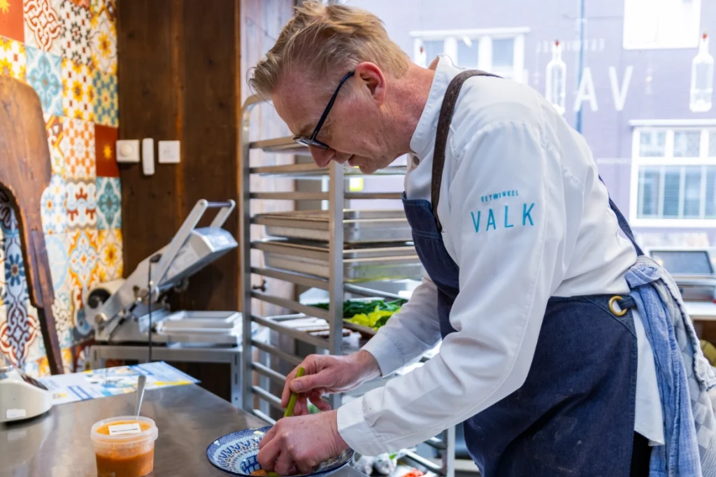 Eigenaar John Valk dekt huisgemaakte vissoep op in de winkel